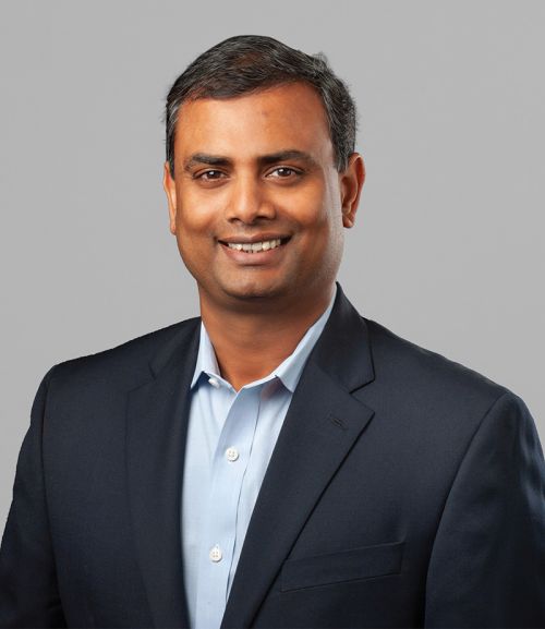 Professional headshot of a businessman in a dark suit with a light blue shirt.