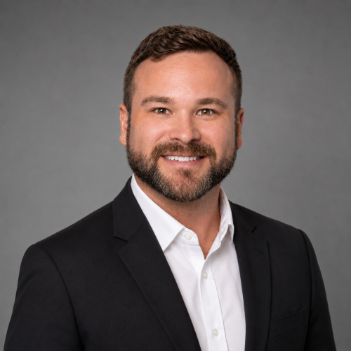 Professional headshot of a man in a white shirt and blazer