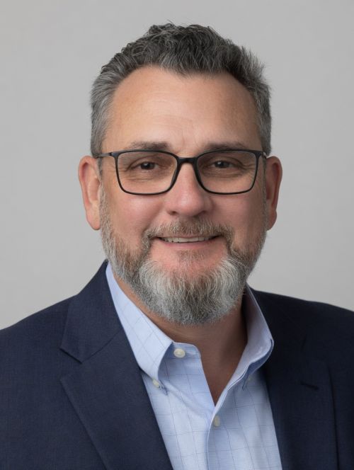 Professional headshot of man in a blue shirt