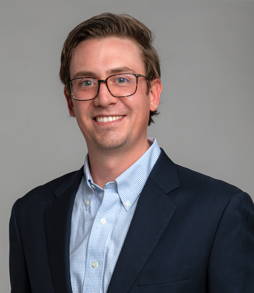 Professional headshot of a young man in business attire.