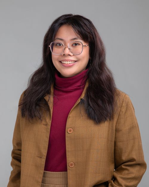 Professional headshot of a woman with long brown hair in a black long-sleeved top.